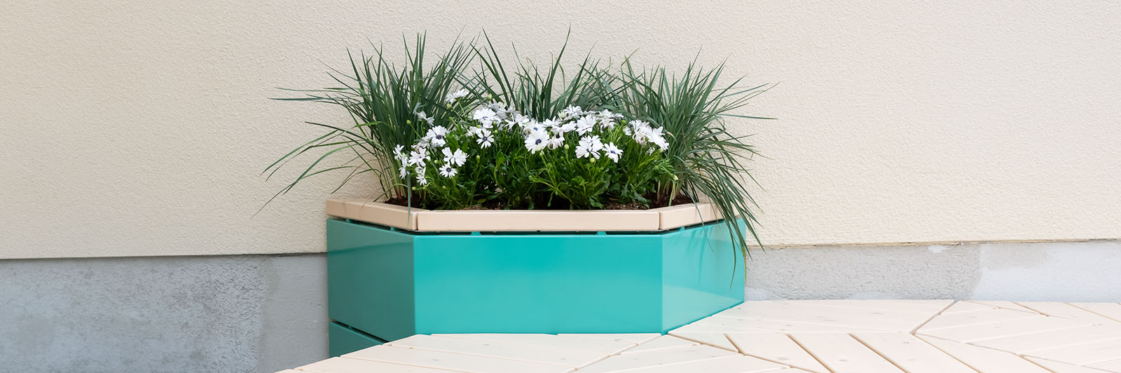 A mounted hex planted with plants inside, the planter is blue with wooden detail and is part of a casual seating arrangement.